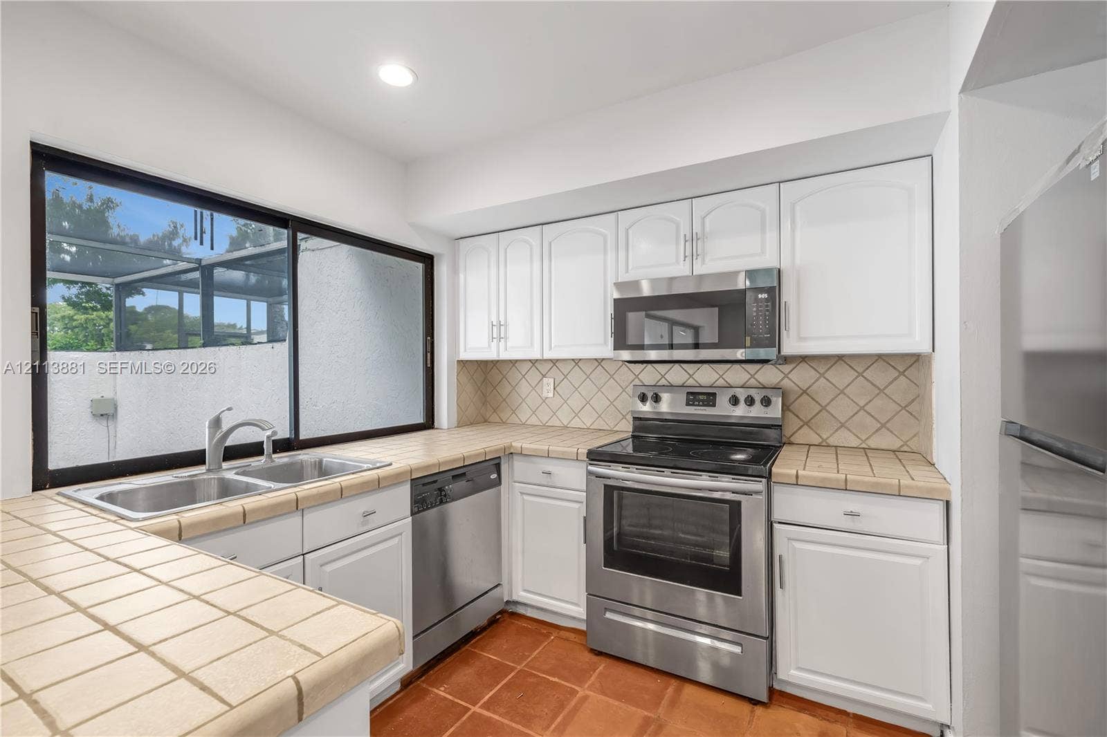 3886 Meadow Lane, #250, Hollywood, FL 33021 Kitchen featuring white cabinetry, stainless steel appliances, tiled countertops, a double-basin sink, and ceramic tile flooring