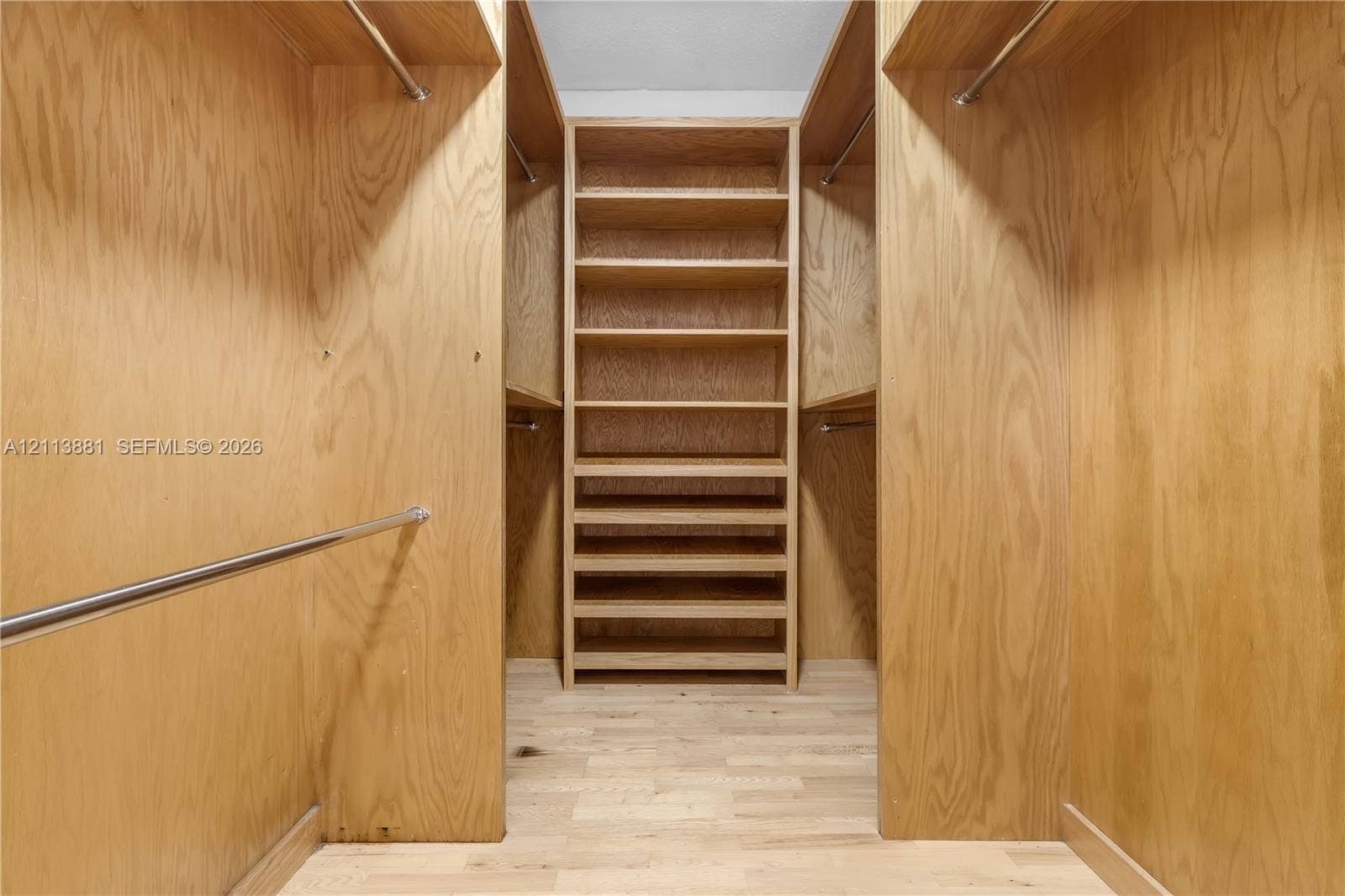 3886 Meadow Lane, #250, Hollywood, FL 33021 Walk-in closet featuring custom wood-finished cabinetry, integrated shelving, tiered storage drawers, and metal clothing rods