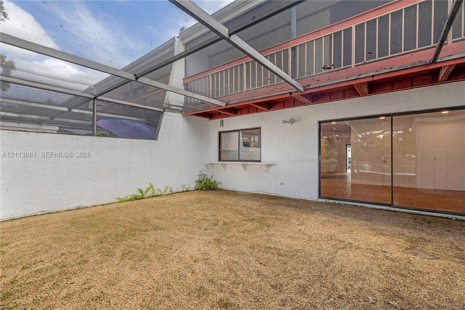 3886 Meadow Lane, #250, Hollywood, FL 33021 Screened outdoor area featuring a stucco wall, an upper-level balcony with a railing, and large sliding glass doors