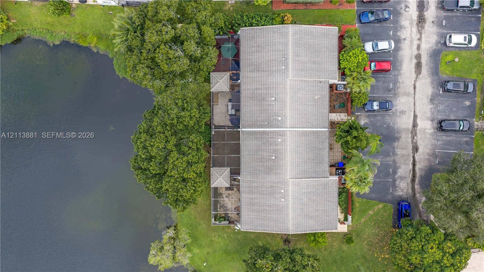 3886 Meadow Lane, #250, Hollywood, FL 33021 Aerial perspective of a multi-unit property featuring water frontage, an expansive screened-in patio area, mature trees, and designated surface parking