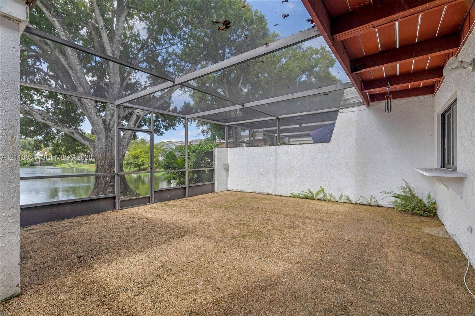 3886 Meadow Lane, #250, Hollywood, FL 33021 Screen-enclosed patio featuring exposed wood-beam ceiling, textured stucco wall, and exterior pass-through window overlooking water