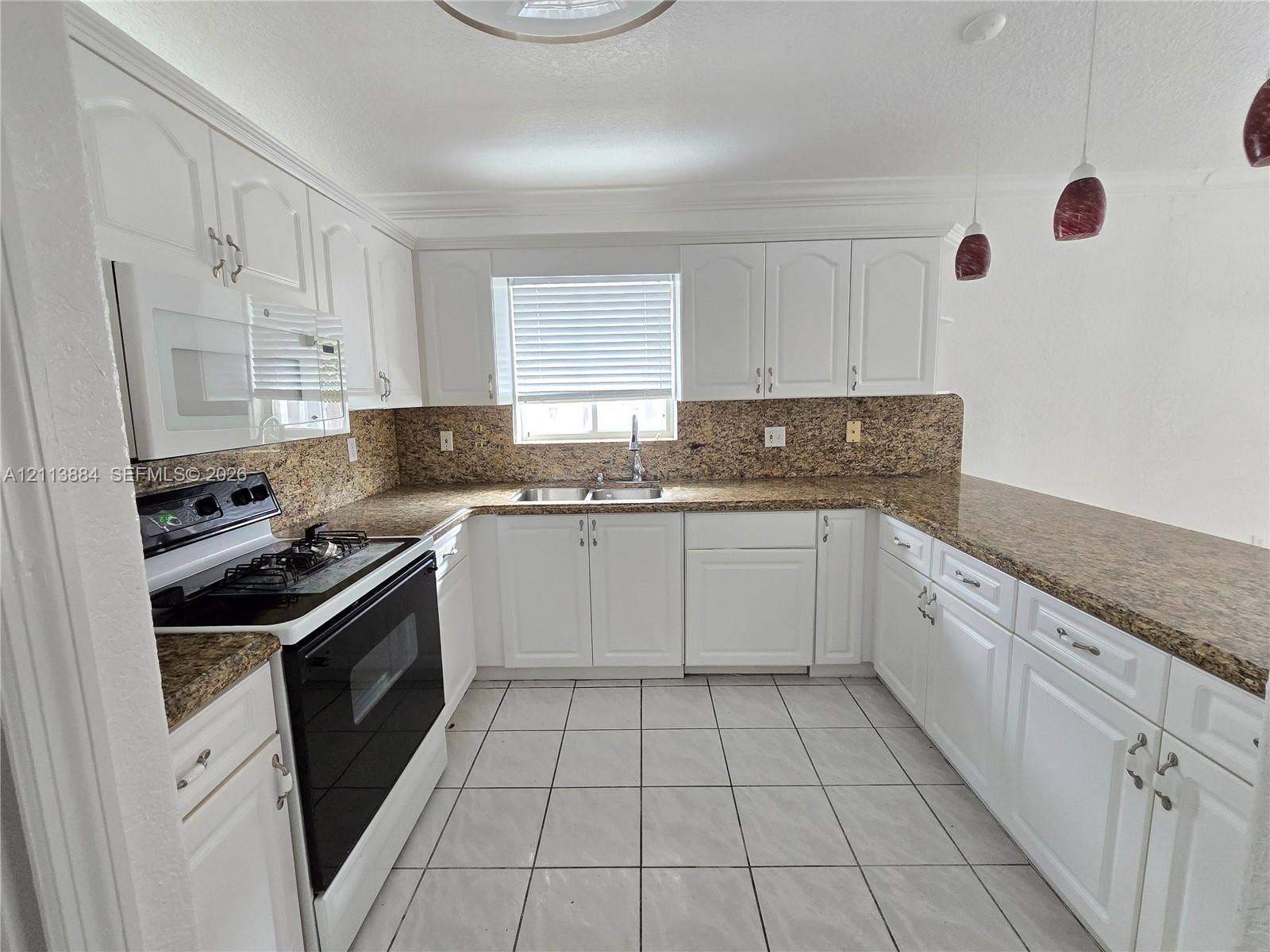 7456 W 34th Court, Hialeah, FL 33018 Kitchen featuring white cabinetry, stone-finish countertops, tile flooring, dual-basin sink, and integrated microwave