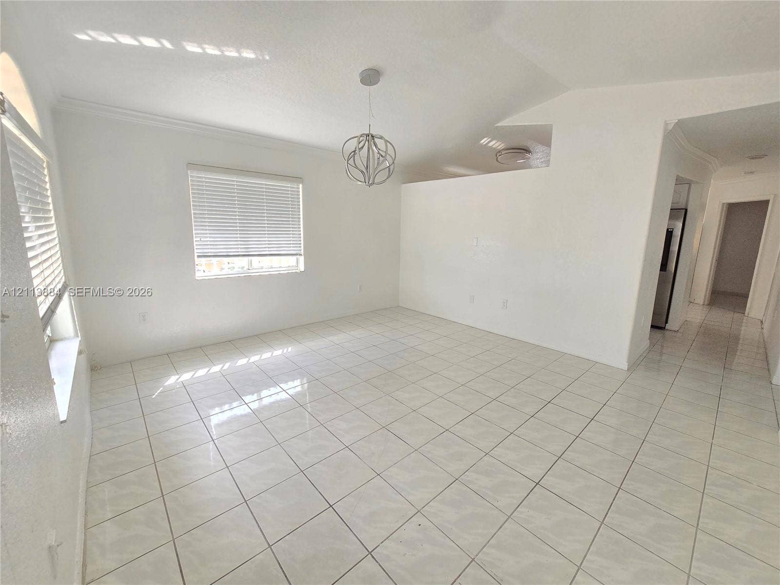 7456 W 34th Court, Hialeah, FL 33018 Open-concept room featuring light tile flooring, high vaulted ceilings, architectural archway accents, and a contemporary spherical pendant light fixture