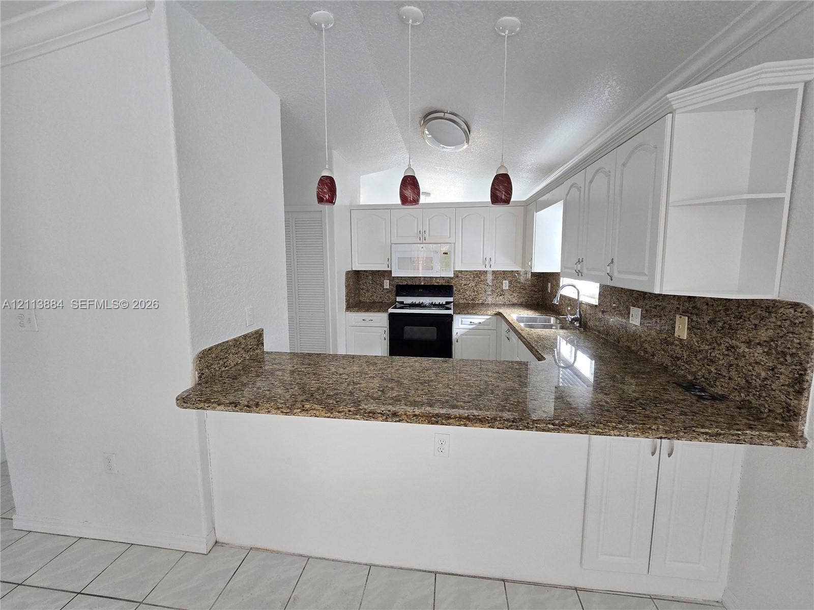 7456 W 34th Court, Hialeah, FL 33018 Kitchen featuring stone-finish countertops, white cabinetry, tile flooring, three pendant lights, and a built-in oven
