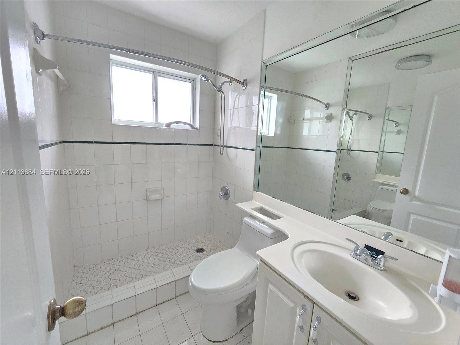 7456 W 34th Court, Hialeah, FL 33018 Bathroom featuring a walk-in shower with white tile surround, vanity with an integrated basin, large wall-mounted mirror, and tile flooring