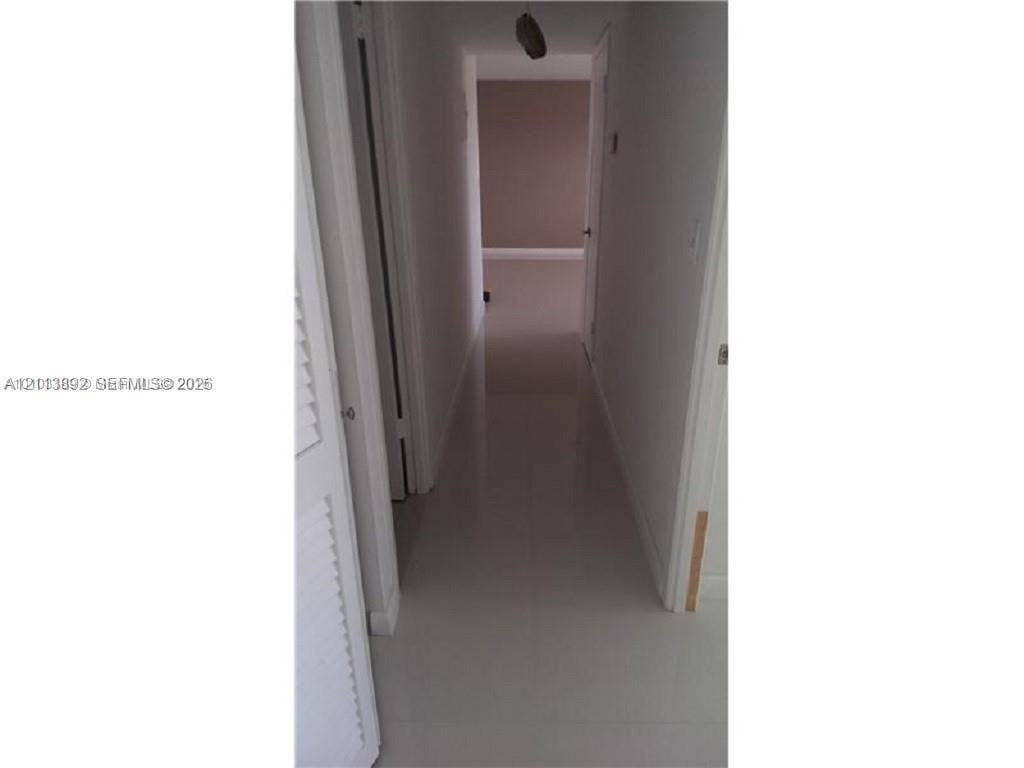 401 Golden Isles Drive, #509, Hallandale Beach, FL 33009 Hallway featuring neutral-toned tile flooring and louvered closet doors