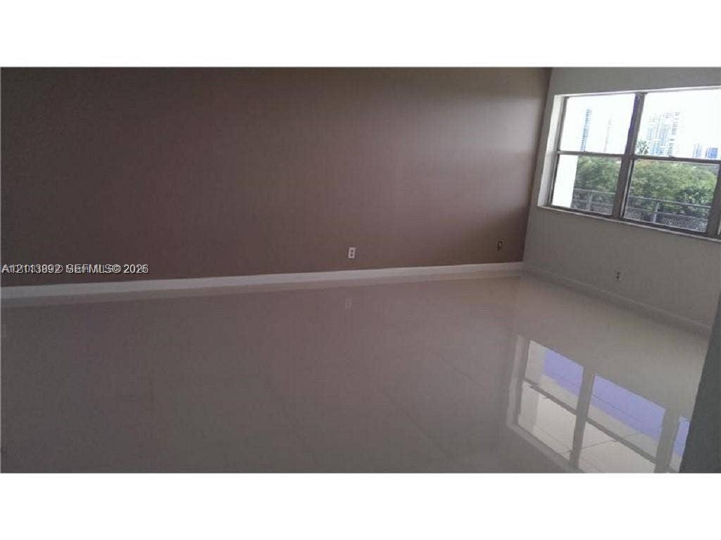 401 Golden Isles Drive, #509, Hallandale Beach, FL 33009 Spacious room featuring polished neutral-toned tile flooring and a large multi-pane window