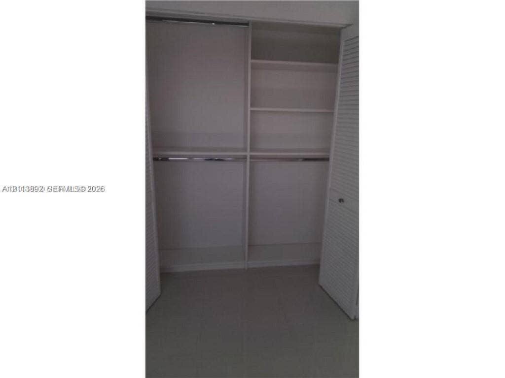 401 Golden Isles Drive, #509, Hallandale Beach, FL 33009 Closet featuring louvered bifold doors, integrated shelving, and dual hanging rods