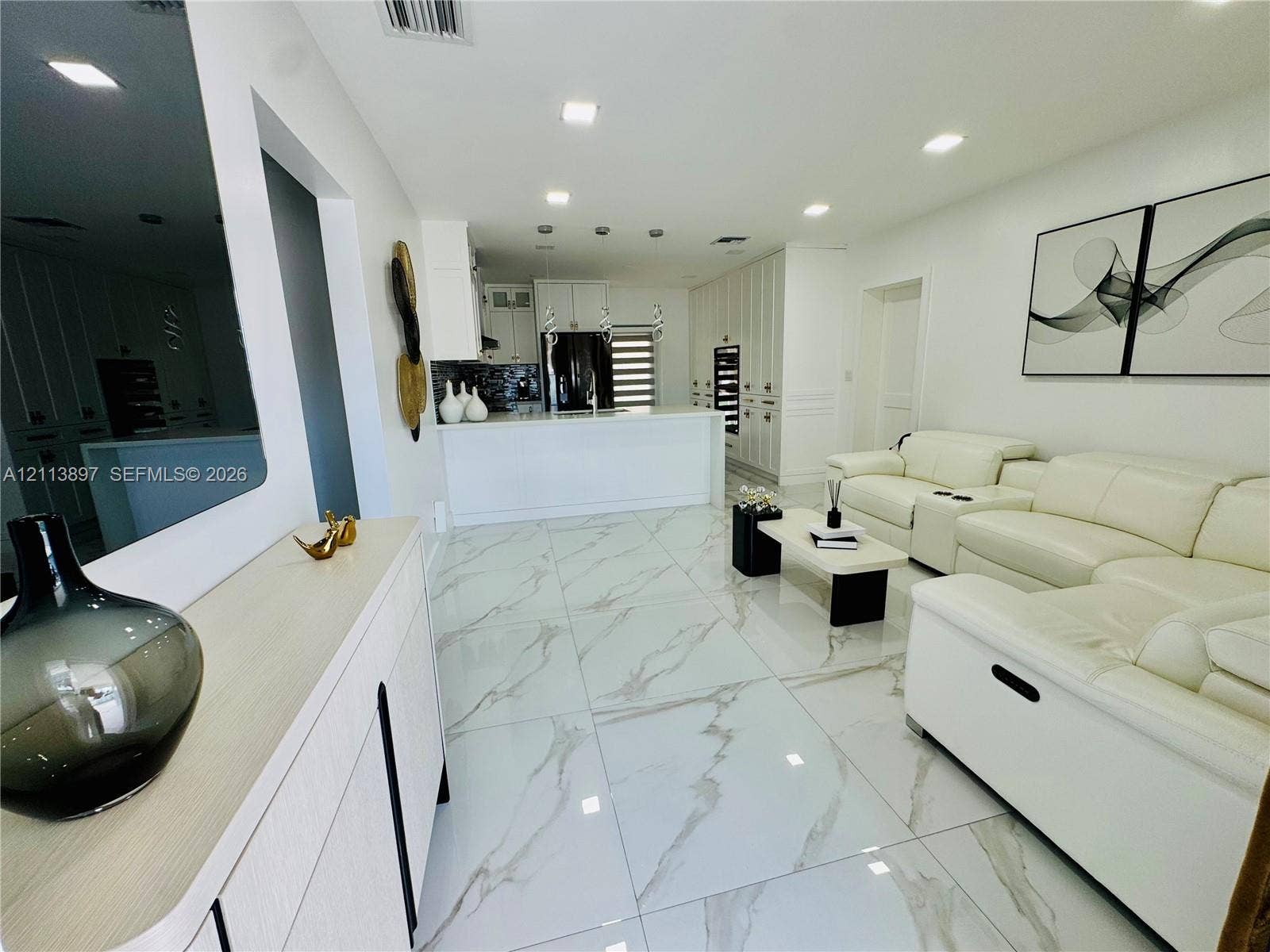 520 E 58th Street, Hialeah, FL 33013 Large-format, light-toned stone-finish floor tiling, white cabinetry with integrated appliances, stone-topped kitchen island, and recessed ceiling lighting