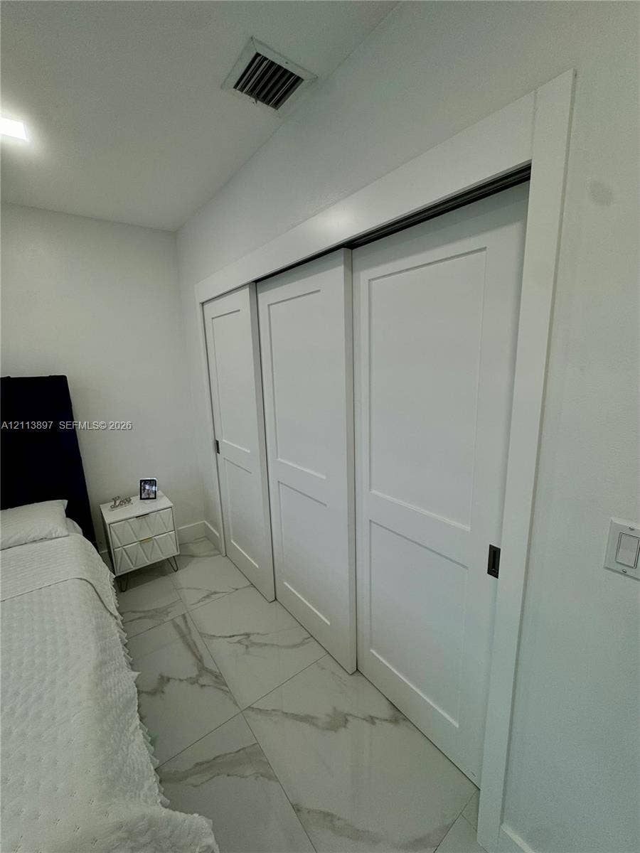 520 E 58th Street, Hialeah, FL 33013 Large-format tile flooring with veining detail and triple-panel sliding closet doors with flush hardware