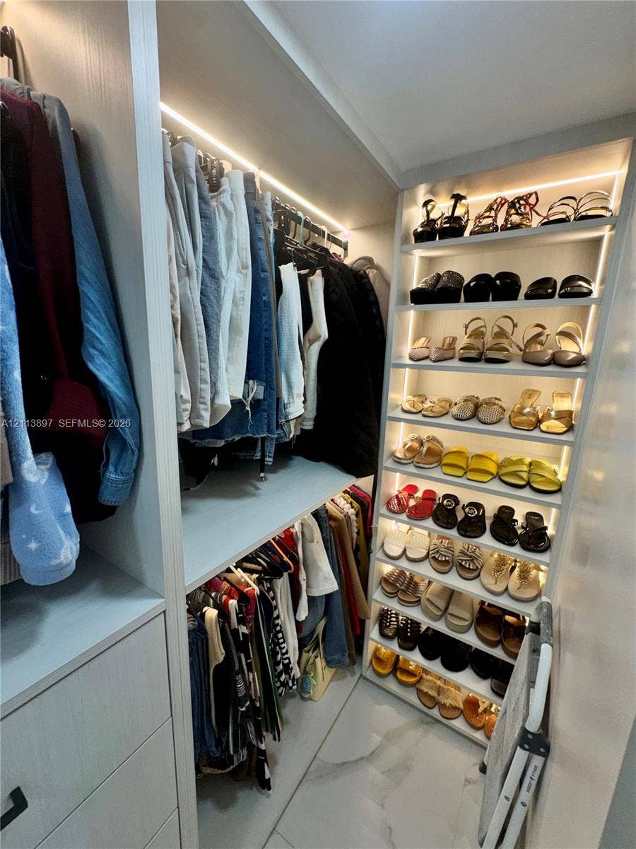 520 E 58th Street, Hialeah, FL 33013 Custom walk-in closet featuring floor-to-ceiling shelving, integrated LED accent lighting, multi-level hanging rods, and large-format tile flooring