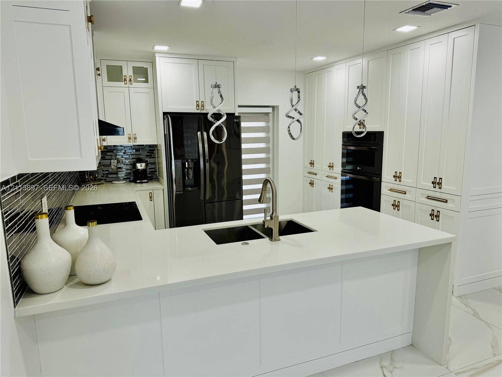 520 E 58th Street, Hialeah, FL 33013 Kitchen featuring white shaker-style cabinetry, quartz countertops, a central island with an undermount sink, built-in wall oven, and geometric pendant lighting