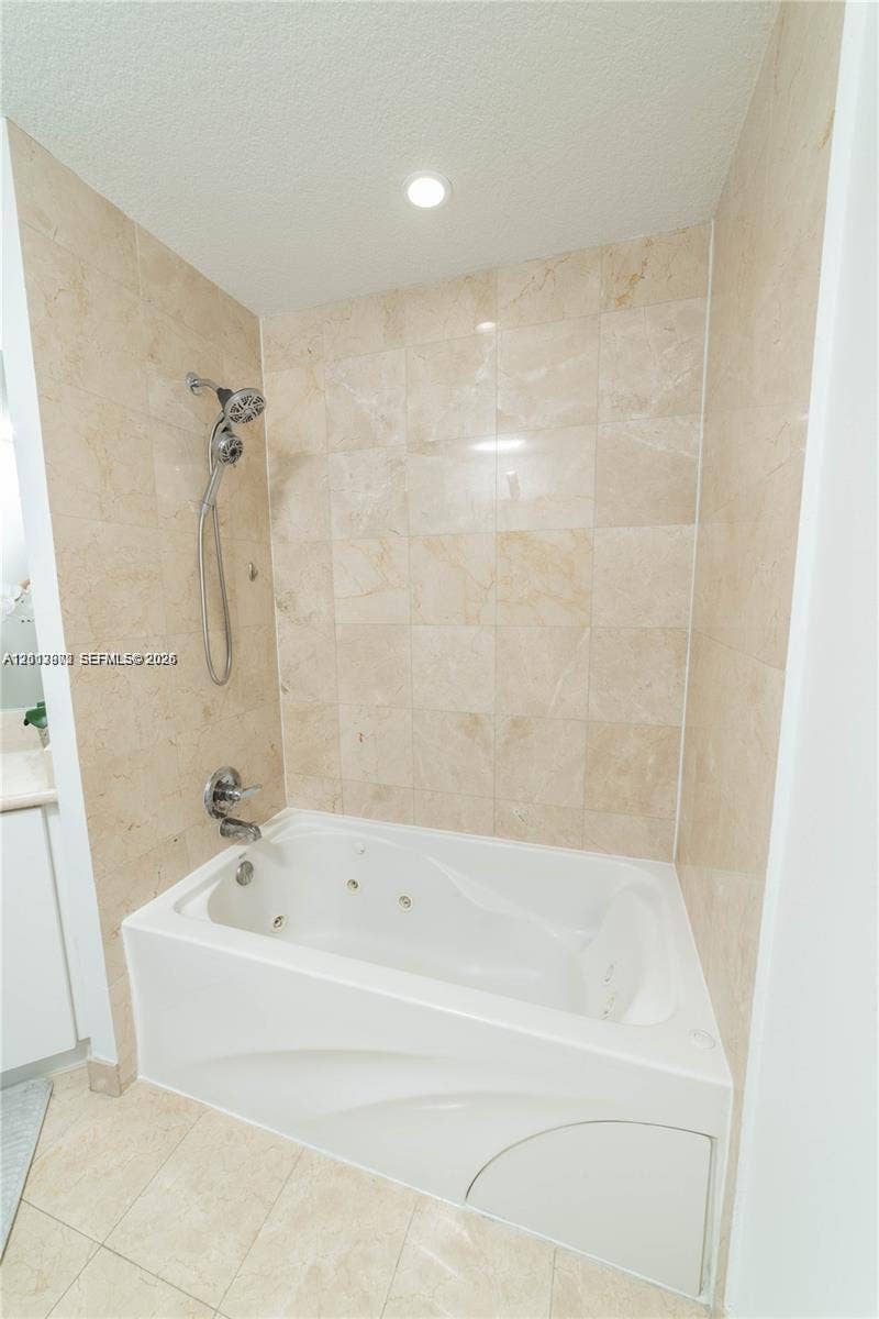 6515 Collins Avenue, #1609, Miami Beach, Miami Beach, FL 33141 Built-in jetted soaking tub featuring full-height light-toned tile surround, integrated handheld shower fixture, and polished chrome faucet