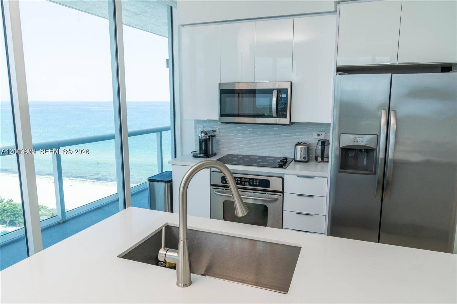 6515 Collins Avenue, #1609, Miami Beach, Miami Beach, FL 33141 Kitchen featuring white high-gloss cabinetry, stainless steel appliances, quartz countertops, a central island with an undermount sink, and floor-to-ceiling windows
