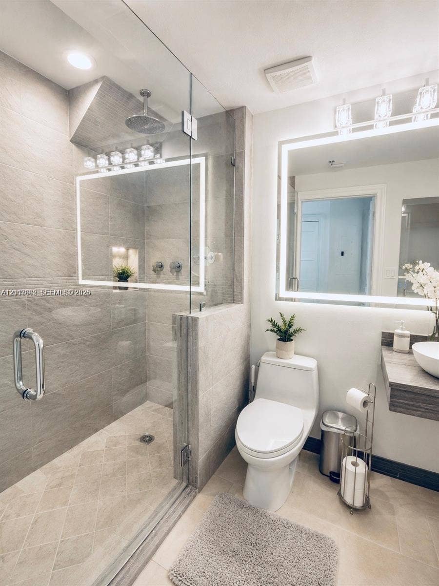 6515 Collins Avenue, #1609, Miami Beach, Miami Beach, FL 33141 Walk-in shower with floor-to-ceiling stone-finish tile, glass enclosure, rainfall showerhead, and integrated wall niche