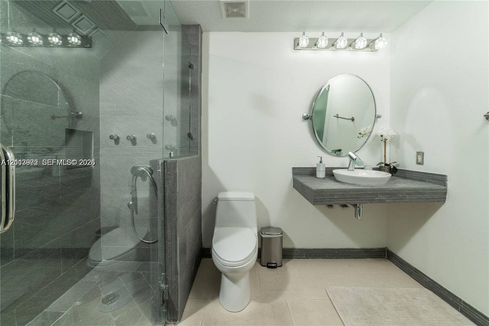 6515 Collins Avenue, #1609, Miami Beach, Miami Beach, FL 33141 Floating vanity with a vessel sink, glass-enclosed shower with tiled walls, and polished light fixtures