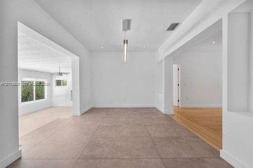 Large-format neutral tile flooring, minimalist linear pendant lighting, recessed ceiling lighting, and wood-finish flooring