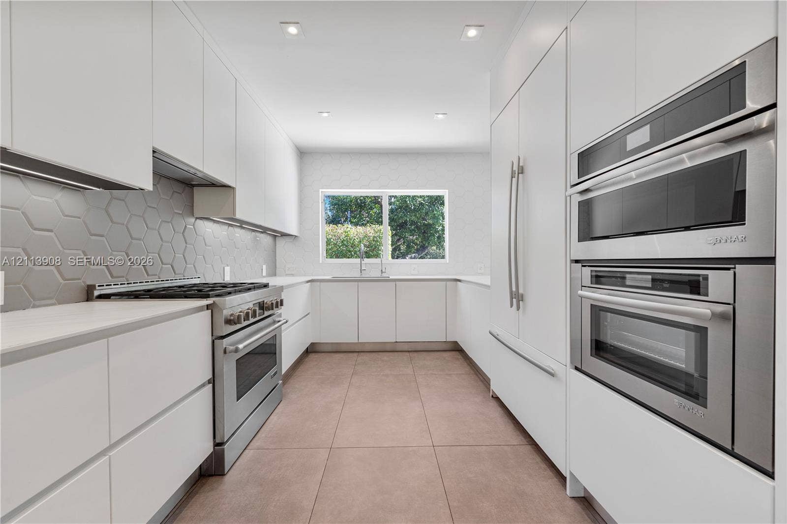 Kitchen featuring flat-panel cabinetry, stainless steel double wall ovens, a gas range, a hexagonal-pattern backsplash, and tile flooring