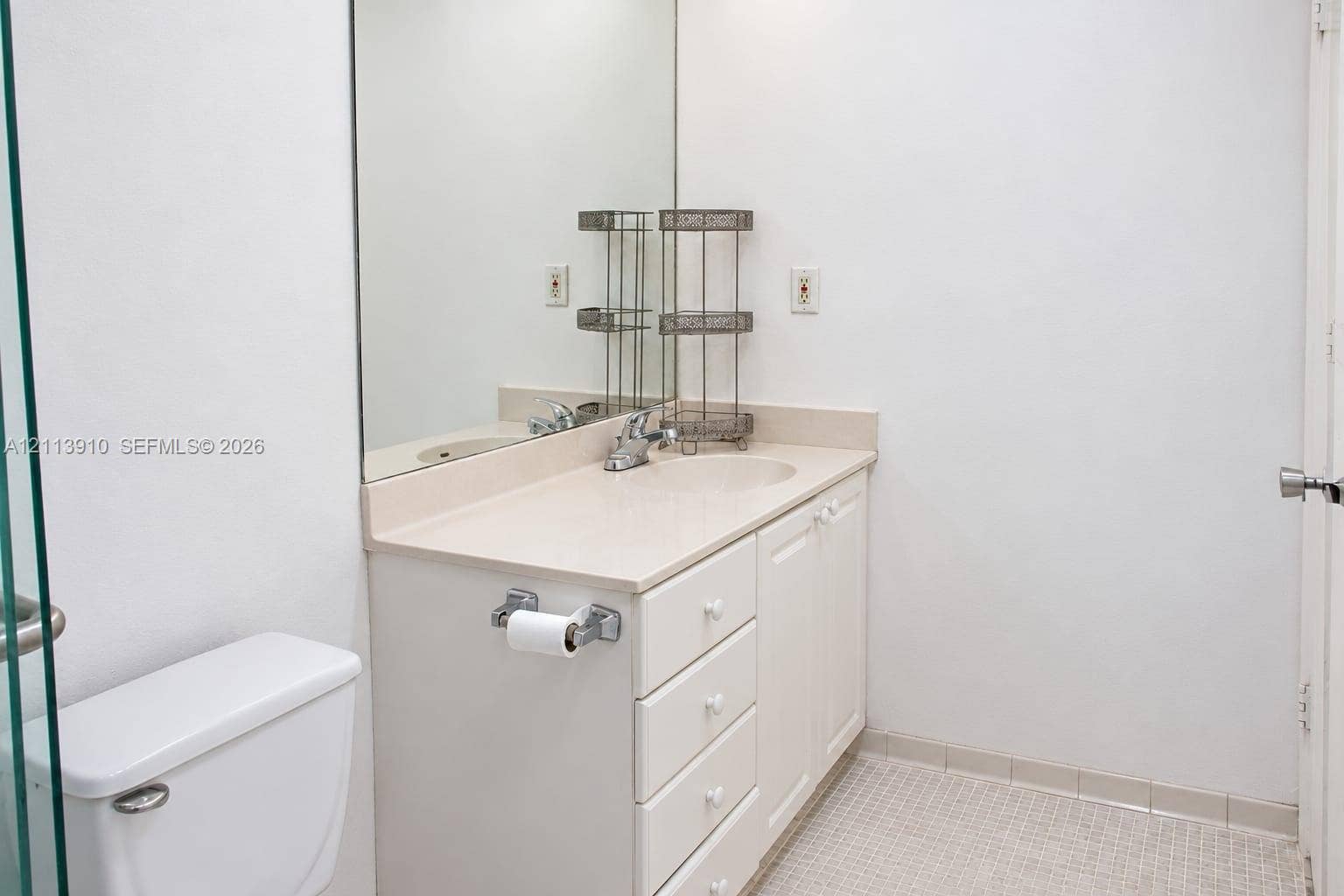 19380 Collins Avenue, #218, Sunny Isles Beach, FL 33160 Vanity featuring a solid-surface countertop with an integrated basin, white cabinetry, a large wall-mounted mirror, and tile flooring