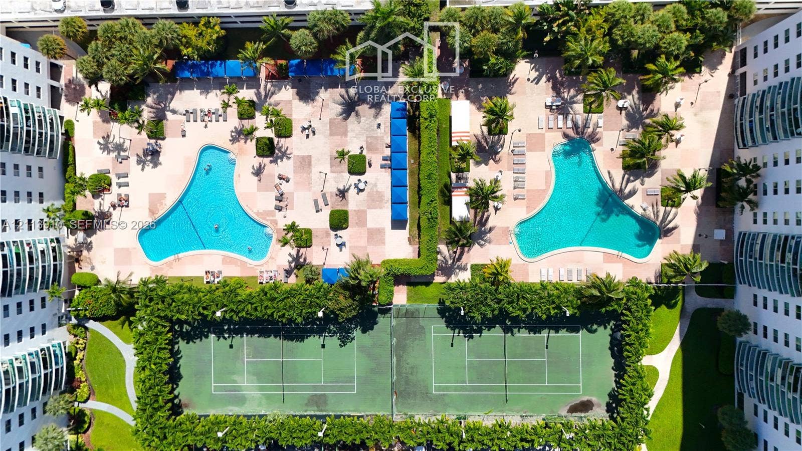 19380 Collins Avenue, #218, Sunny Isles Beach, FL 33160 Recreational area featuring two outdoor swimming pools, two hard-court tennis courts, paved decking, and mature landscaping