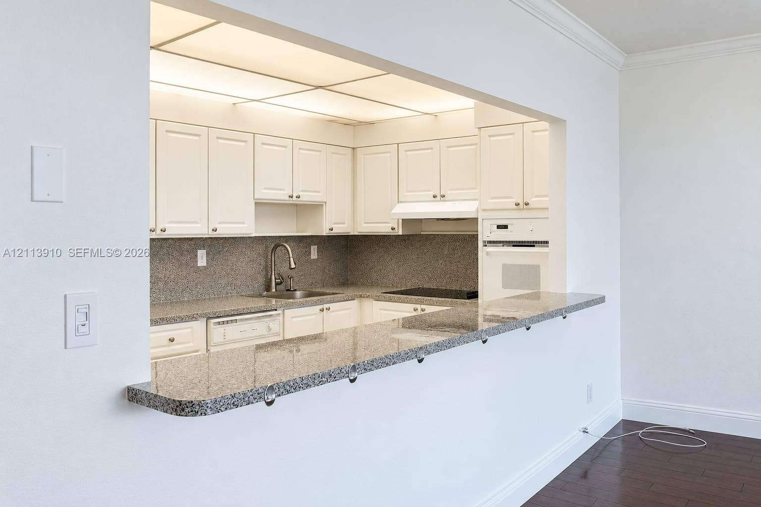 19380 Collins Avenue, #218, Sunny Isles Beach, FL 33160 Kitchen featuring white cabinetry, stone-finish countertops, an integrated cooktop, a built-in oven, and an extended breakfast bar