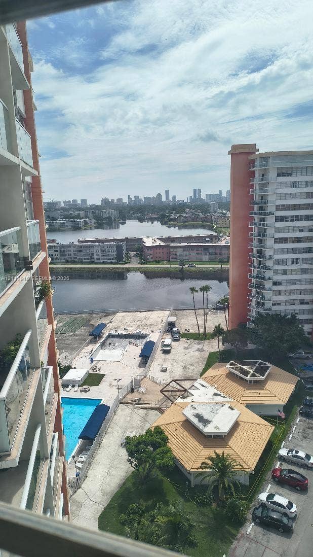 1301 Miami Gardens Drive, #1521 W, Miami, Miami, FL 33179 High-rise exterior with glass-panel balcony railings, swimming pool, and landscape area featuring palm trees and tile-roof pavilions