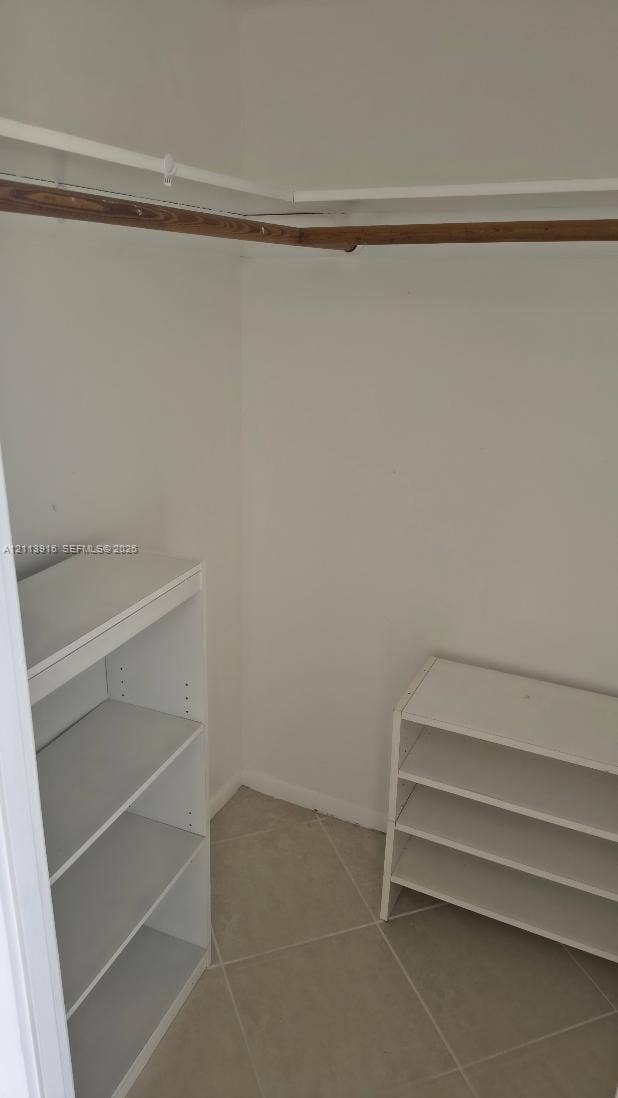 1301 Miami Gardens Drive, #1521 W, Miami, Miami, FL 33179 Storage space featuring tile flooring, built-in shelving units, and an overhead closet rod