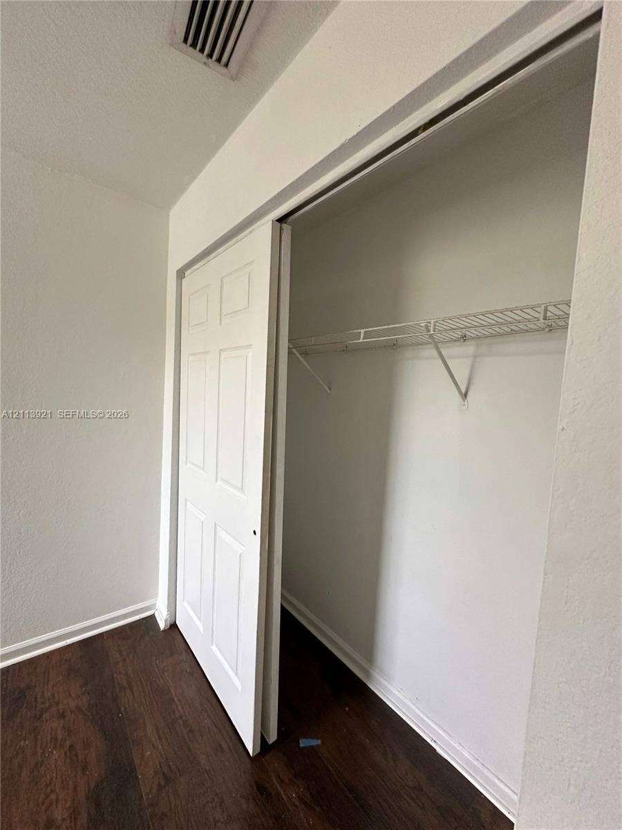 824 Summit Lake Drive, West Palm Beach, West Palm Beach, FL 33406 Closet featuring six-panel sliding doors and built-in wire shelving, finished with wood-finish flooring