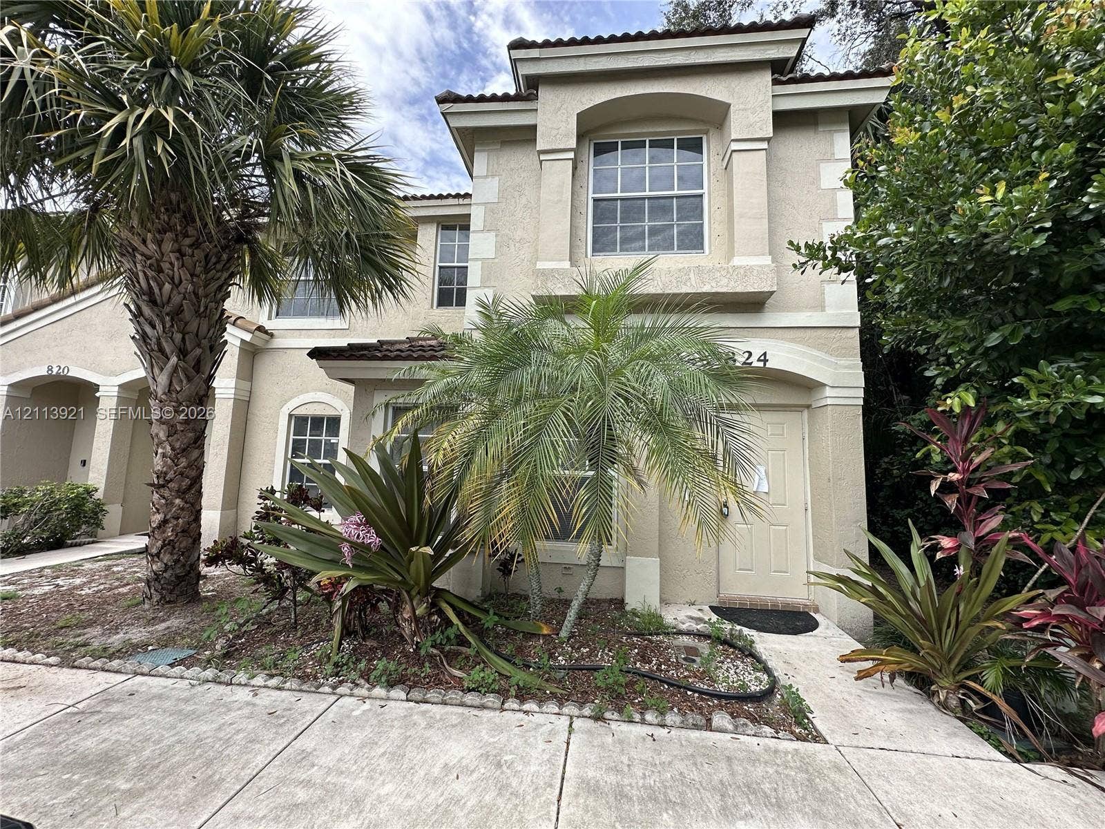 824 Summit Lake Drive, West Palm Beach, West Palm Beach, FL 33406 Two-story stucco exterior featuring arched entryways, decorative corner quoins, tile roof accents, and mature tropical landscaping