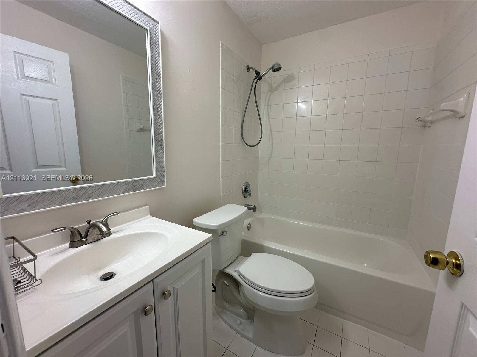 824 Summit Lake Drive, West Palm Beach, West Palm Beach, FL 33406 Bathroom featuring a white vanity cabinet, integrated sink with metallic dual-handle faucet, framed wall mirror, and tub-shower combination with tiled surround