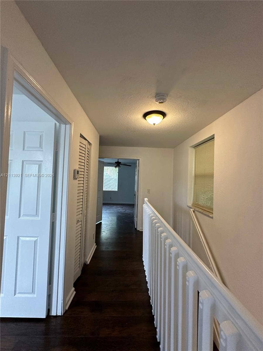 824 Summit Lake Drive, West Palm Beach, West Palm Beach, FL 33406 Hallway featuring wood-finish flooring, white paneled doors, louvered closet doors, and a white baluster railing
