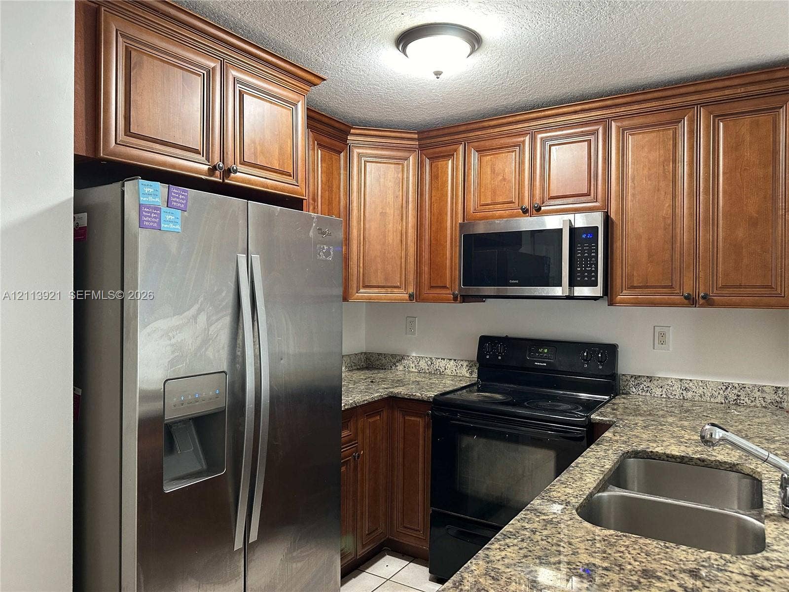 824 Summit Lake Drive, West Palm Beach, West Palm Beach, FL 33406 Kitchen featuring stained wood cabinetry, stone-patterned countertops, stainless steel side-by-side refrigerator, built-in microwave, and stainless steel dual-basin sink