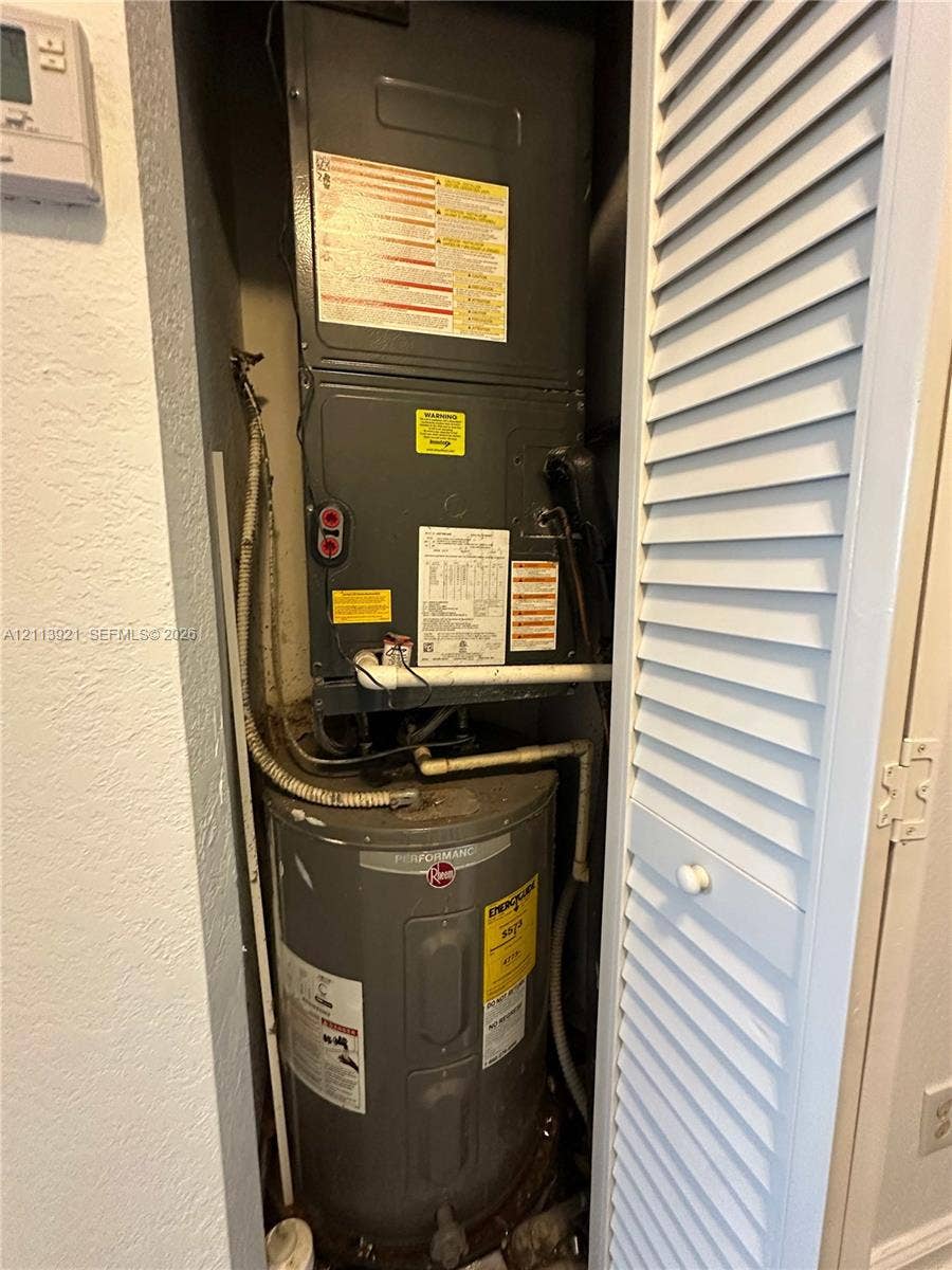 824 Summit Lake Drive, West Palm Beach, West Palm Beach, FL 33406 Utility closet featuring a dedicated HVAC air handler and a vertical water heater enclosed behind a white louvered door