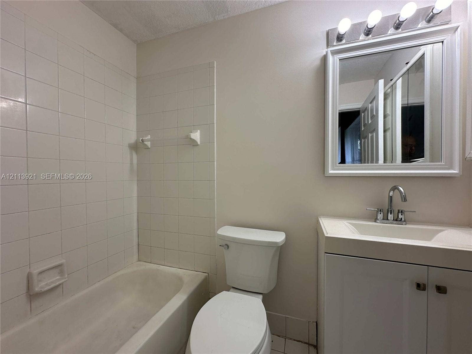 824 Summit Lake Drive, West Palm Beach, West Palm Beach, FL 33406 Bathroom featuring a white vanity with an integrated sink, polished chrome faucet, white square-tile shower surround, and a framed vanity mirror with an overhead multi-light fixture