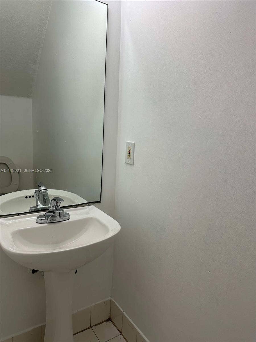 824 Summit Lake Drive, West Palm Beach, West Palm Beach, FL 33406 White pedestal sink featuring a chrome faucet, large rectangular mirror, and neutral tile flooring