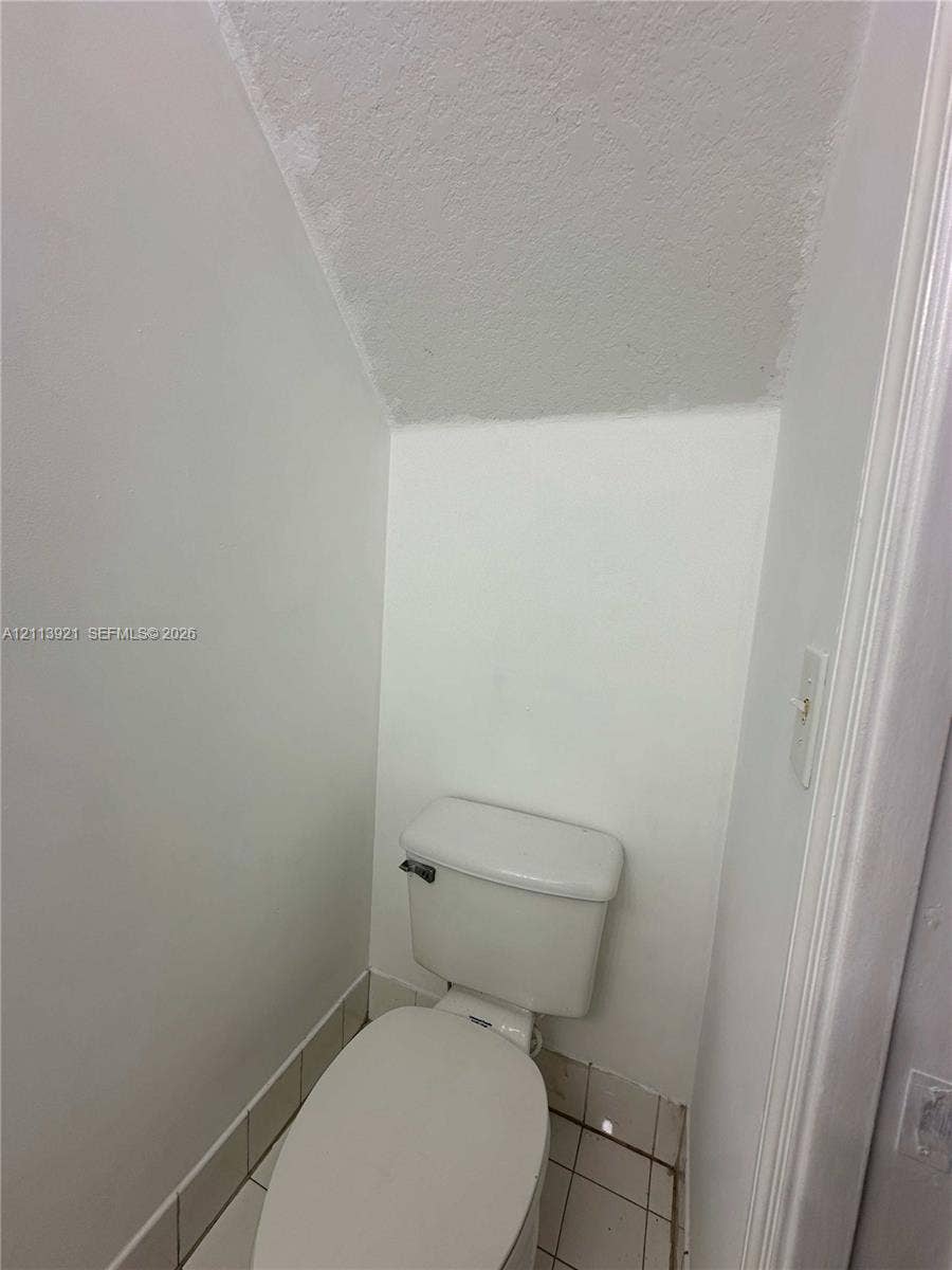 824 Summit Lake Drive, West Palm Beach, West Palm Beach, FL 33406 White toilet with an elongated bowl, tile flooring, and angled ceiling