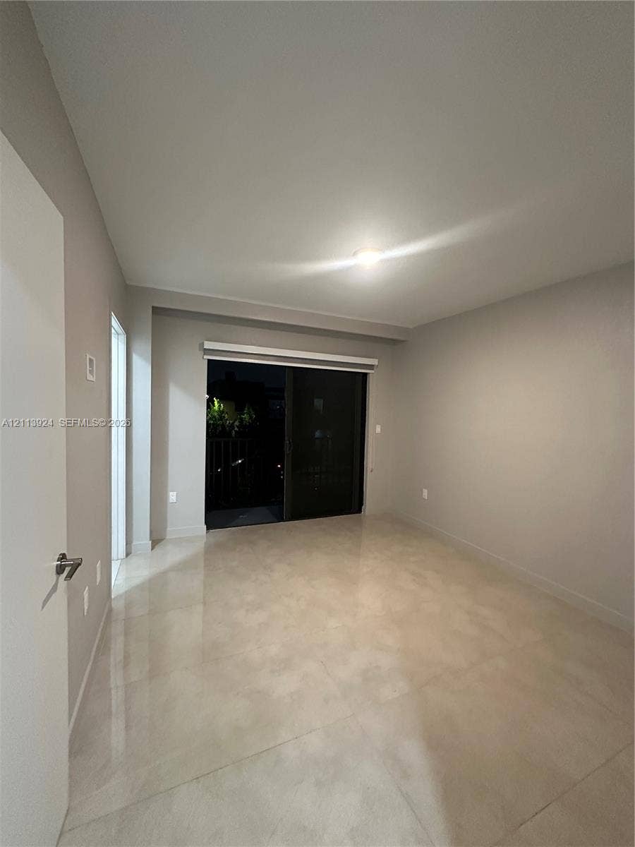 14569 SW 261st Terrace, #14569, Homestead, Homestead, FL 33032 Room featuring large-format tile flooring, neutral wall tones, and a sliding glass door providing external access