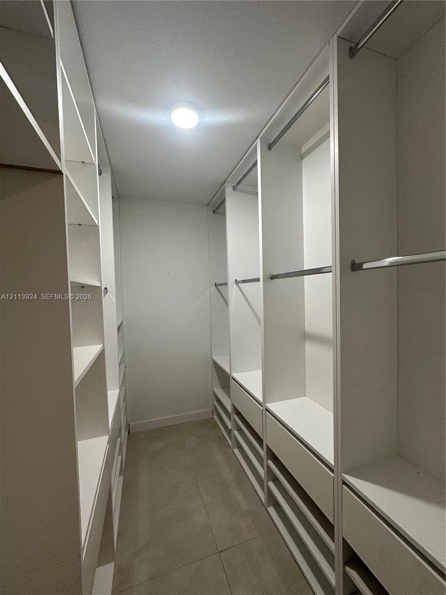 14569 SW 261st Terrace, #14569, Homestead, Homestead, FL 33032 Walk-in closet featuring white custom built-in cabinetry, tiered shelving, integrated clothing rods, and tile flooring