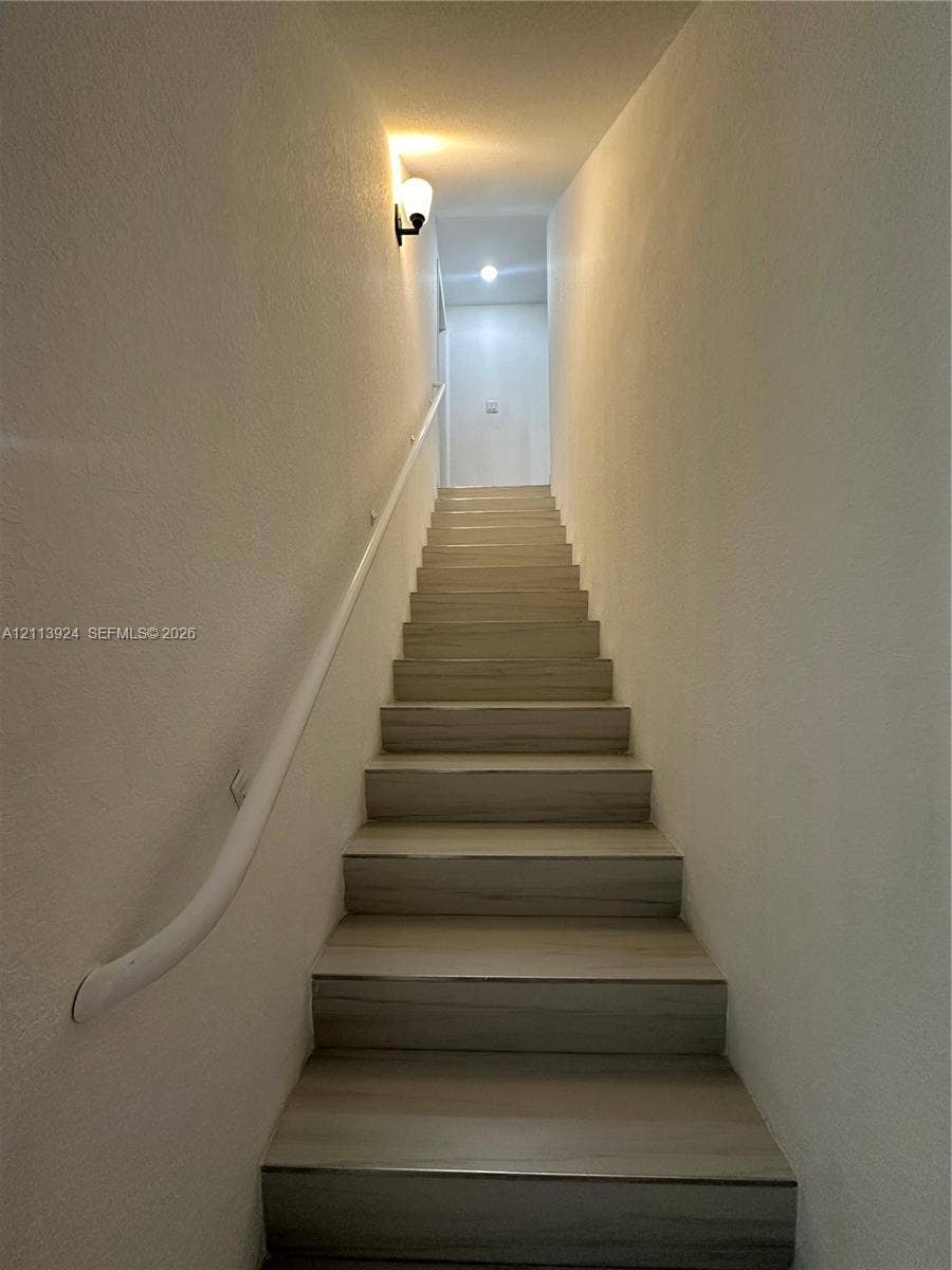 14569 SW 261st Terrace, #14569, Homestead, Homestead, FL 33032 Staircase featuring wood-finish treads and a wall-mounted handrail