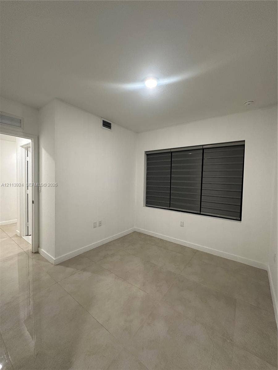 14569 SW 261st Terrace, #14569, Homestead, Homestead, FL 33032 Neutral interior featuring large-format ceramic tile flooring, solid white walls, and a recessed window with installed horizontal dual-shade blinds