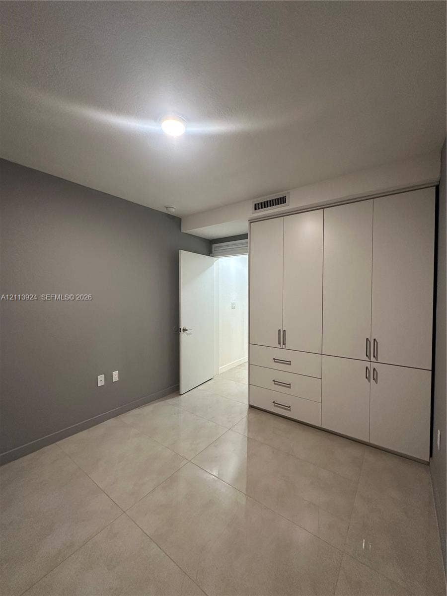 14569 SW 261st Terrace, #14569, Homestead, Homestead, FL 33032 Room featuring large-format tile flooring, built-in floor-to-ceiling white cabinetry with integrated drawers, and a ceiling-mounted light fixture