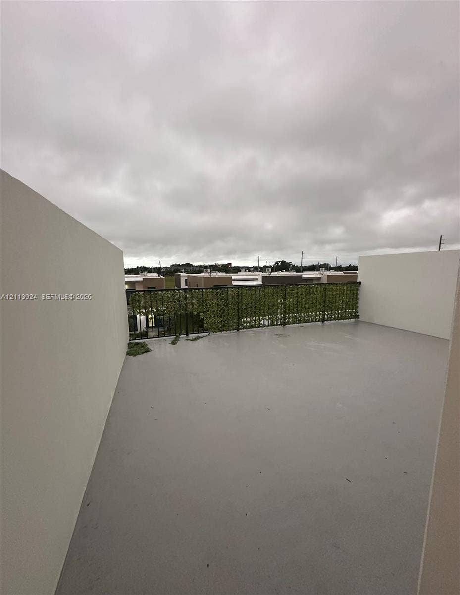 14569 SW 261st Terrace, #14569, Homestead, Homestead, FL 33032 Rooftop terrace featuring smooth concrete flooring, solid privacy walls, and a metal railing with integrated greenery