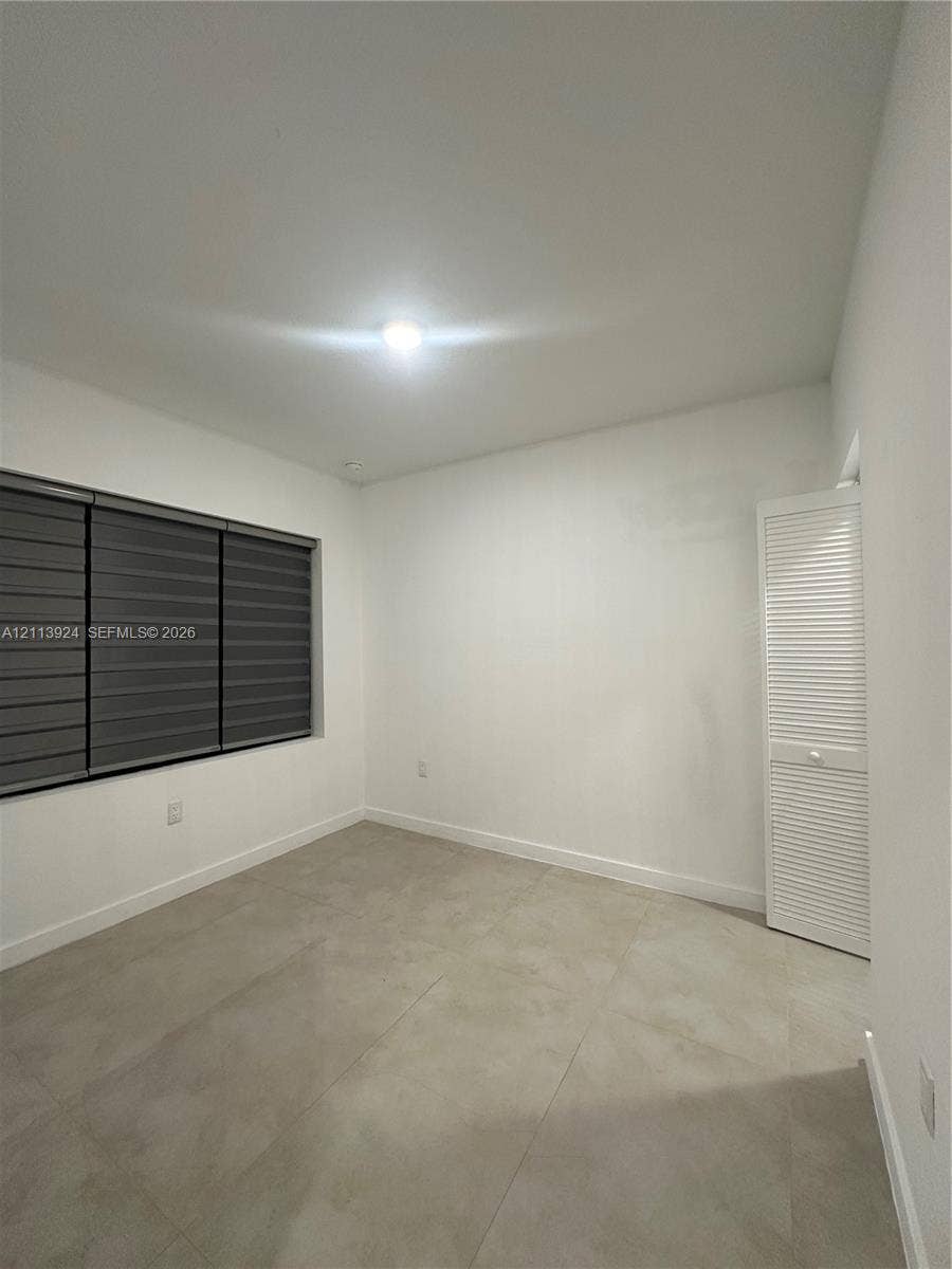 14569 SW 261st Terrace, #14569, Homestead, Homestead, FL 33032 Room featuring large-format tile flooring, white walls, louvered closet doors, and multi-band window shades