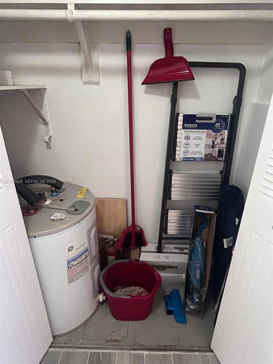 2008 Jackson Street, #D3, Hollywood, FL 33020 Utility closet featuring an electric water heater, built-in shelving, and a hanging rod