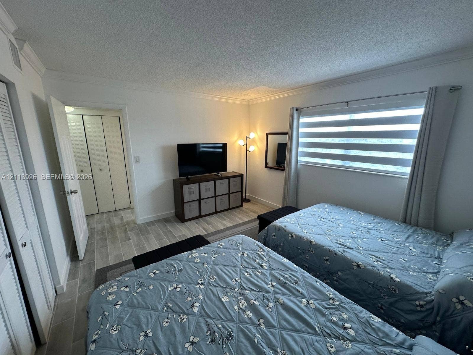 2008 Jackson Street, #D3, Hollywood, FL 33020 Room featuring wood-finish tile flooring, dual-panel closet doors, textured ceilings, and striped privacy window shades