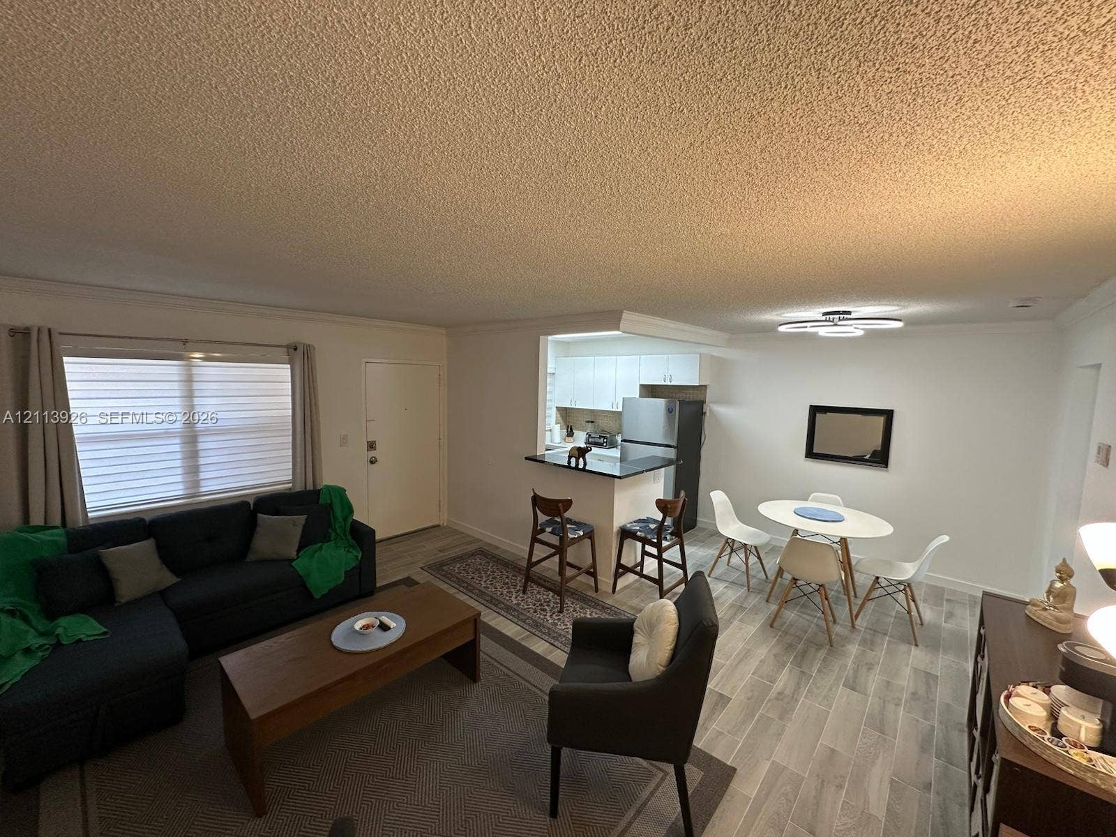 2008 Jackson Street, #D3, Hollywood, FL 33020 Open-concept interior featuring wood-finish flooring, a kitchen breakfast bar with countertop seating, and a modern circular LED light fixture
