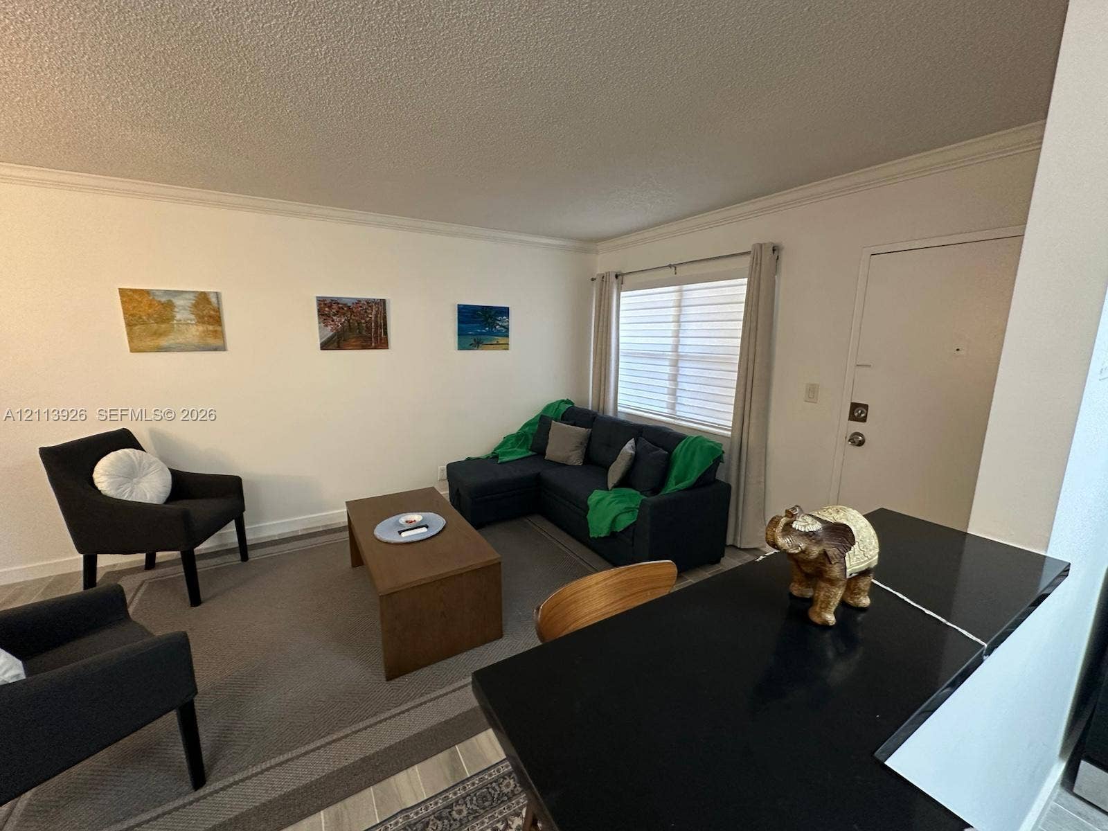2008 Jackson Street, #D3, Hollywood, FL 33020 Neutral interior featuring wood-finish flooring, a solid-surface countertop with an integrated breakfast bar, and a window with horizontal blinds
