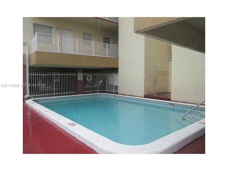 2008 Jackson Street, #D3, Hollywood, FL 33020 Swimming pool featuring a concrete deck, integrated steps, and metal handrails, bordered by a white perimeter fence and multi-level structure