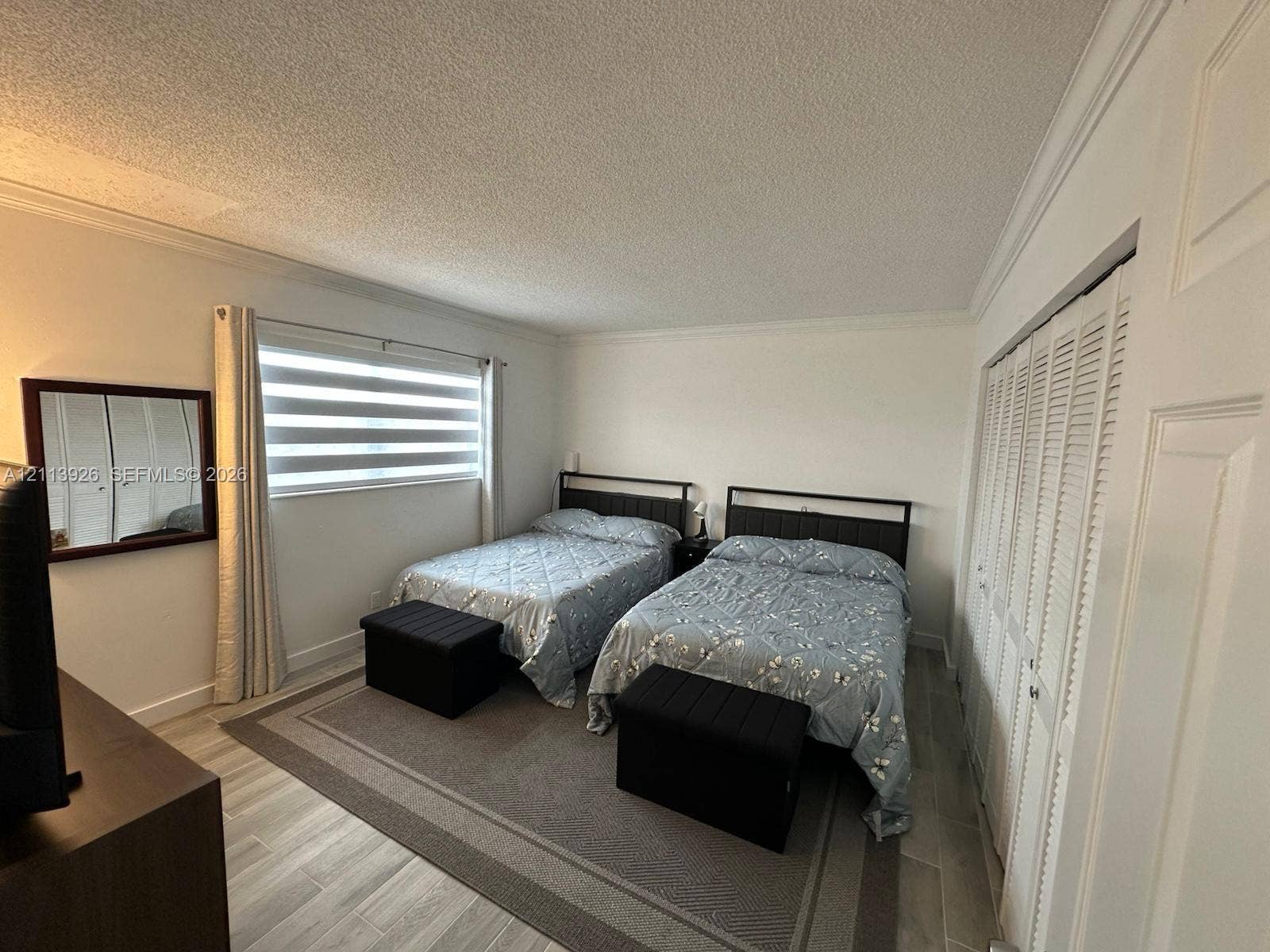 2008 Jackson Street, #D3, Hollywood, FL 33020 Bedroom featuring wood-finish tile flooring, dual louvered-style closet doors, a wide window with integrated horizontal blinds, and crown molding
