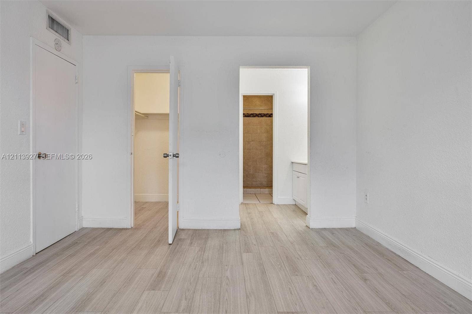 4900 NW 79th Avenue, #202, Doral, Doral, FL 33166 Neutral-toned wood-finish flooring, walk-in closet with built-in shelving, and vanity with stone-finish countertop